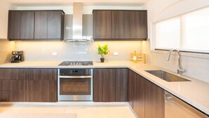 Eine moderne Küche mit dunklen Holzschränken, einer Edelstahl-Dunstesse, einem Einbauofen und einer Spüle mit zwei Becken.