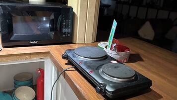 A kitchen with a microwave, a coffee machine, and a small refrigerator.