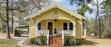 A yellow single-story house with a porch, a front door, and a small front yard.