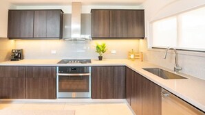 A modern kitchen with dark wood cabinets, stainless steel appliances, and a large window providing natural light. - Stunning Condo at The Pearl in Jaco Beach 4B (Jacó)