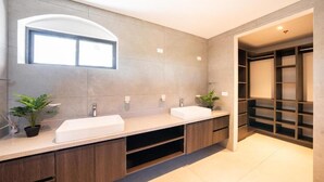 A modern bathroom with two sinks, a large mirror, and a built-in shelving unit. - Stunning Condo at The Pearl in Jaco Beach 6B (Jacó)