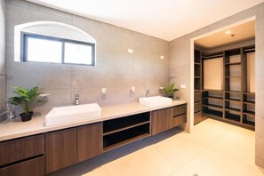 A modern bathroom with two sinks, a large mirror, and a built-in shelving unit. - Stunning Condo at The Pearl in Jaco Beach 6B (Jacó)