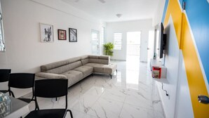 Un soggiorno moderno con un divano componibile, un tavolo da pranzo con sedie e una TV a parete.
