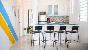 Una cucina moderna con mobili bianchi, un piano di lavoro nero e quattro sgabelli neri.