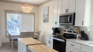 A modern kitchen with white cabinetry, a central island, a microwave, and a coffee machine. - Spacious 6-bedroom house in wonderful Ocean Lakes (Myrtle Beach)
