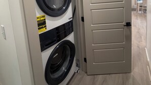 A laundry room with two front-loading washing machines, a door with a handle, and a light switch on the wall. - Spacious 6-bedroom house in wonderful Ocean Lakes (Myrtle Beach)