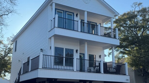 A two-story building with a balcony on the upper floor. - Spacious 6-bedroom house in wonderful Ocean Lakes (Myrtle Beach)