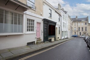 A street with a row of white buildings, one with a pink door labeled "The Old Crescent Bakery." - The Old Crescent Bakery - Beautiful Bath Townhouse (Bath)