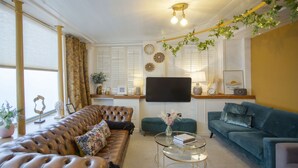 Ein Wohnzimmer mit einem braunen Ledersofa, einem türkisblauen Sofa und einem Glastisch.