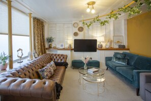 A living room with a brown leather sofa, a teal sofa, and a glass coffee table.