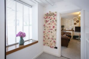 A room with a floral wall decoration, a 'Photo Booth' sign, a brown leather sofa, and a small table with a lamp. - The Old Crescent Bakery - Beautiful Bath Townhouse (Bath)