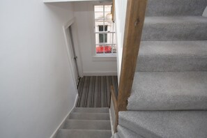 A staircase with a wooden handrail and a carpeted landing.