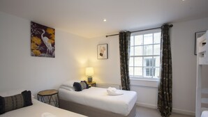 Ein Hotelzimmer mit zwei Betten, einem Fenster mit Vorhängen, einer Lampe und einem Bild an der Wand.