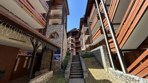 A narrow alleyway with stone walls and wooden balconies, leading to a building with a sign for 'INTERSPORT'. - 40m from ski slopes, 3rd floor, balcony, tv, 35m², Méribel-Mottaret (Méribel - Les Allues)