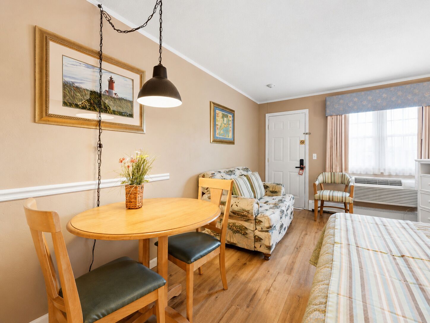 A cozy room with a dining table, chairs, a sofa, a patterned rug, and a hanging light fixture.