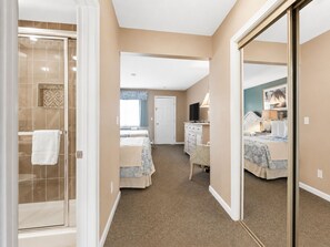 A hotel room with a shower, two beds, a dresser, and a large mirror.