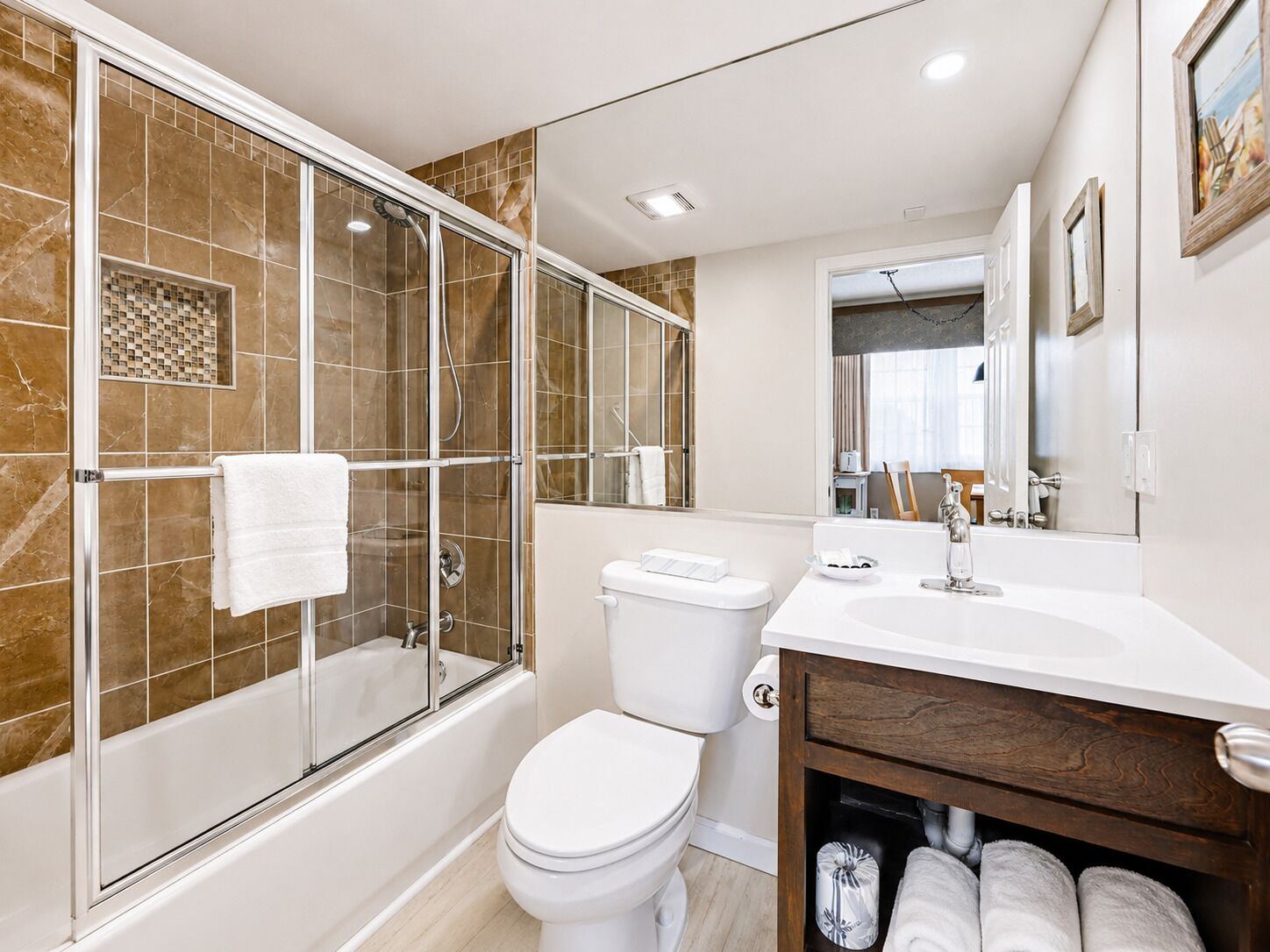 A modern bathroom with a glass-enclosed shower, a white toilet, and a vanity with a mirror.