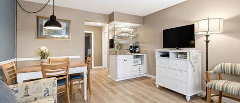 A compact living space with a dining area, kitchenette, and a TV.