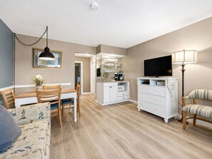 A compact living space with a dining area, kitchenette, and a TV.