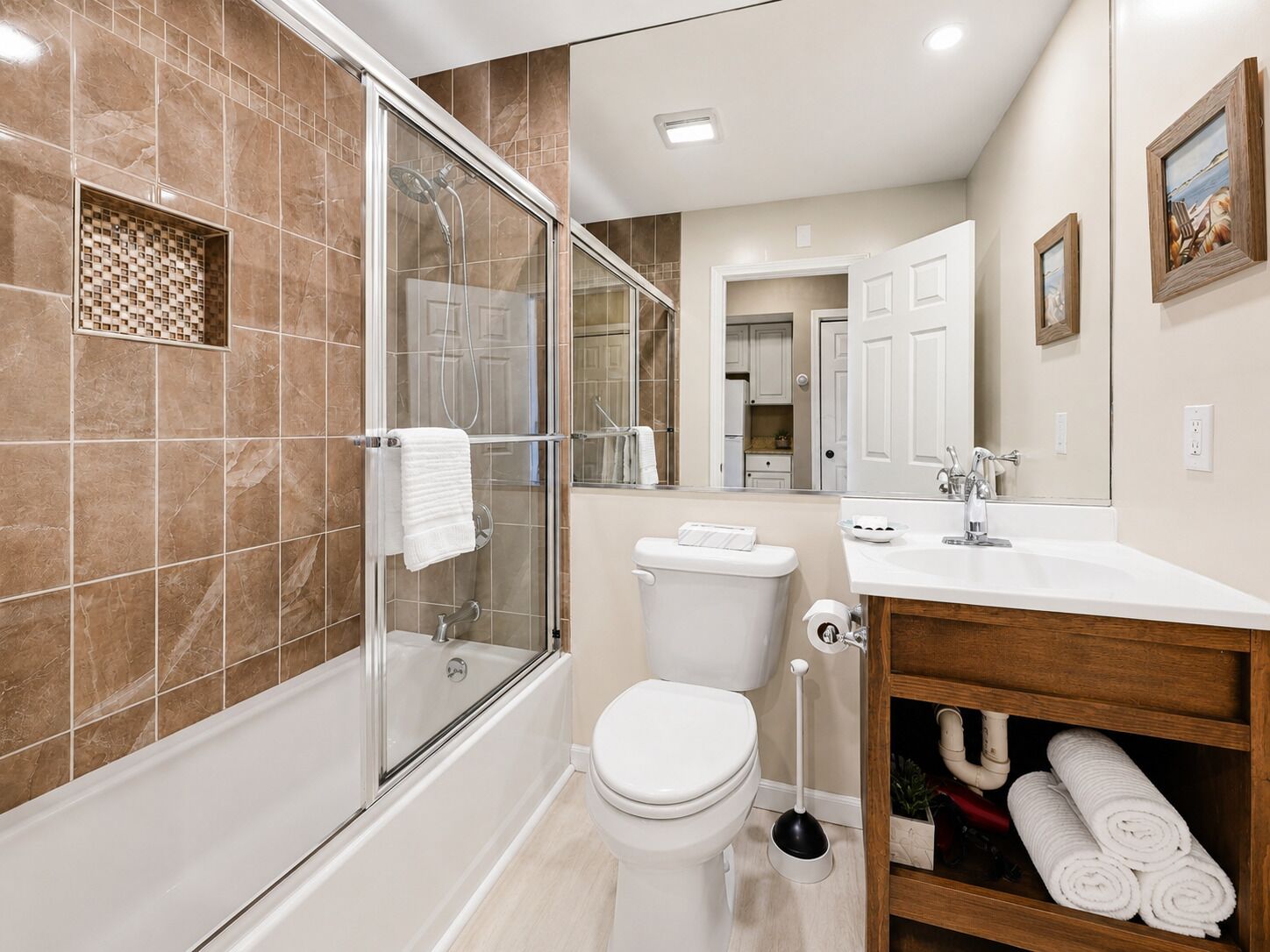 A modern bathroom with a glass-enclosed shower, a toilet, a sink, and a vanity with towels.