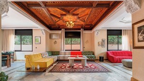 A spacious living area with a high wooden ceiling, a central coffee table, and a red sofa. - 4 Bedroom Villa in Bab Ighli Marrakech Heated Pool Atlas View (Marrakesh)