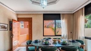 A dining area with a round table set for six, surrounded by six chairs with green upholstery. - 4 Bedroom Villa in Bab Ighli Marrakech Heated Pool Atlas View (Marrakesh)