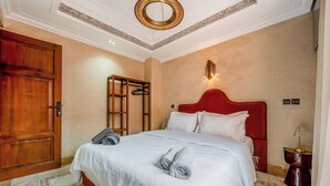 A hotel room with a large bed, a wooden wardrobe, a red headboard, and a small bedside table with a lamp. - 4 Bedroom Villa in Bab Ighli Marrakech Heated Pool Atlas View (Marrakesh)