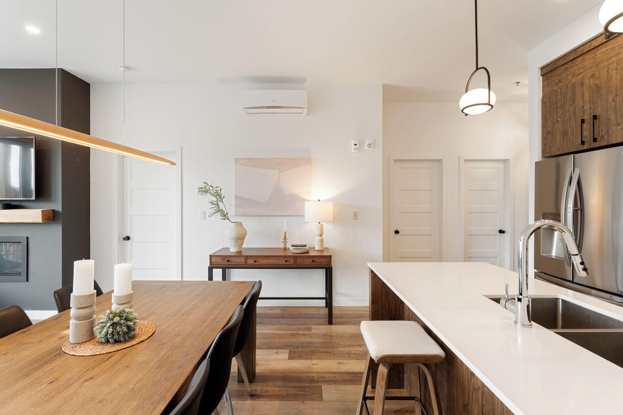 Une cuisine moderne avec une table à manger en bois, des appareils électroménagers intégrés et un luminaire suspendu.