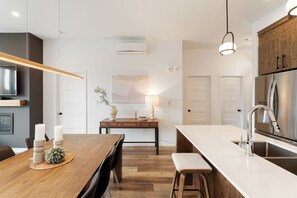 Uma cozinha moderna com uma mesa de jantar de madeira, forno embutido e geladeira de aço inoxidável.