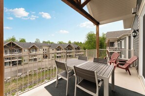 Eine überdachte Terrasse im Freien mit Tisch und Stühlen, mit Blick auf eine Reihe von Reihenhäusern.