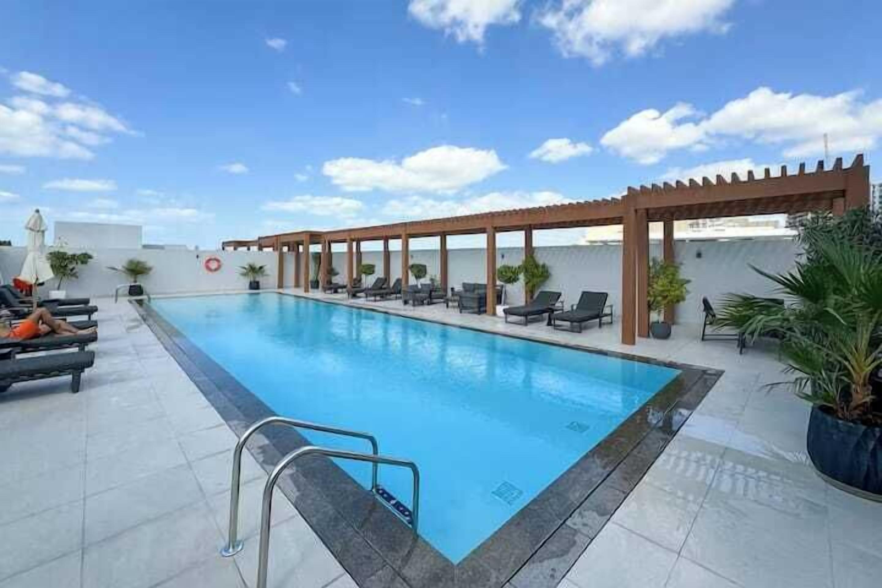 Una piscina con lettini da sole e un pergolato.