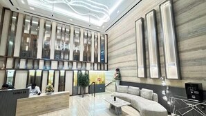 Un hall d’entrée moderne avec un comptoir d’accueil, un espace salon et une grande fenêtre.