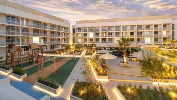 Un hôtel à étages, doté d’une piscine extérieure et de divers espaces de loisirs, notamment une aire de jeux et des coins salon.