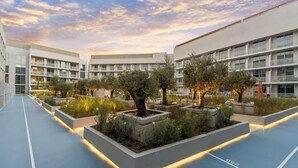 Une cour d’hôtel moderne, dotée d’espaces de détente en plein air, entourée d’immeubles à plusieurs étages avec des balcons.