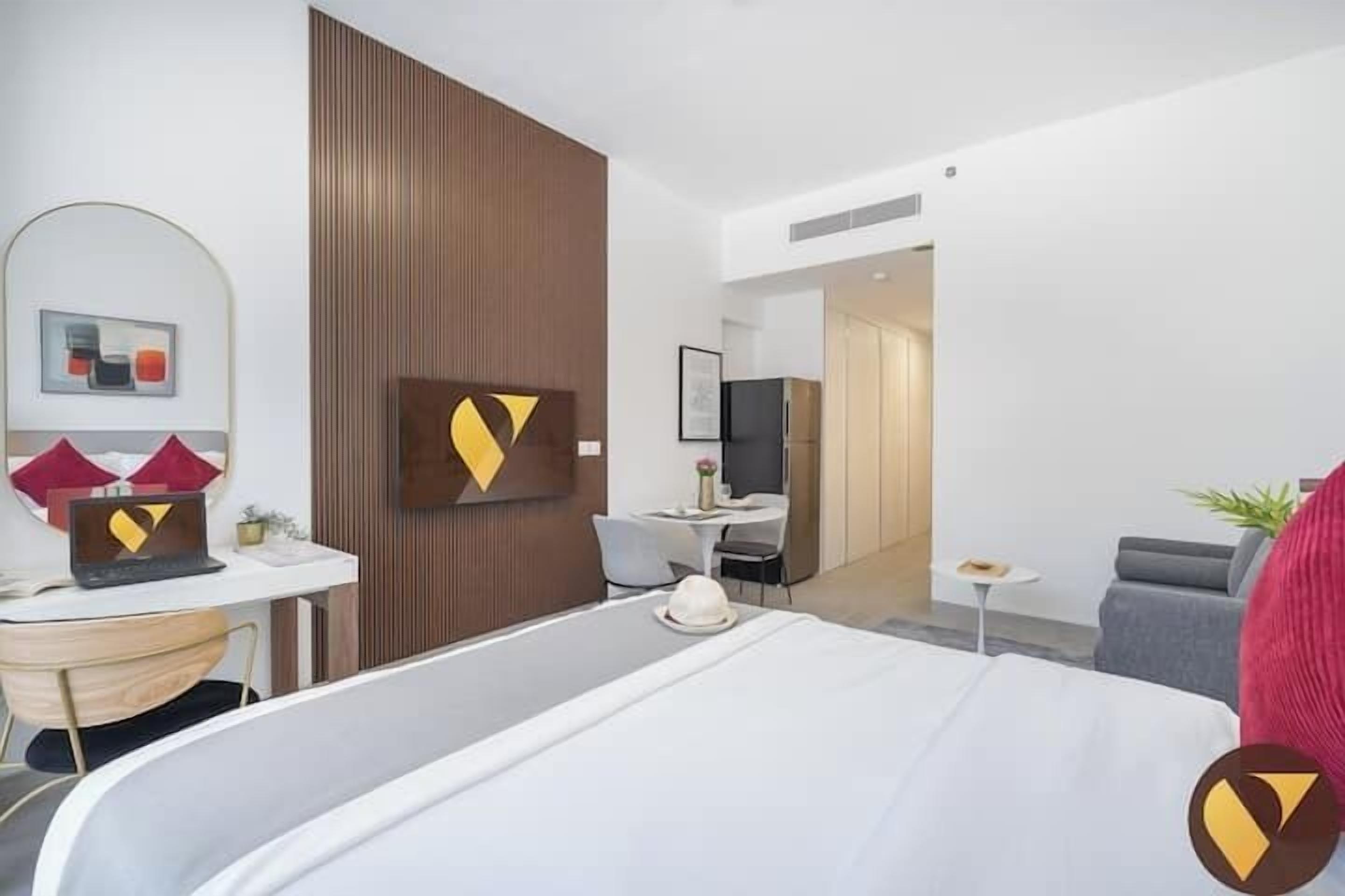 Een moderne hotelkamer met een groot bed, een bureau, een stoel en een bijzettafeltje.