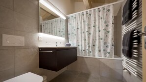 Une salle de bain comprenant des toilettes, un lavabo, un miroir et un espace douche.