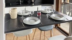 Ett modernt kök med en svart bänkskiva, vita skåp och en hängande taklampa.
