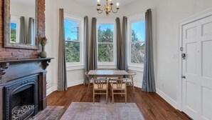 A room with a fireplace, a dining table with chairs, a chandelier, and large windows with curtains. - Walk everywhere. Stay in comfort. Experience New Orleans like a local, (New Orleans)