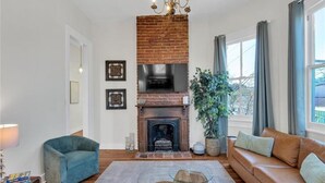 A living room with a brick fireplace, a sofa, a blue armchair, and a coffee table. - Walk everywhere. Stay in comfort. Experience New Orleans like a local, (New Orleans)