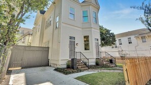 A two-story residential building with a gabled roof, a front entrance with a staircase, and a fenced yard. - Walk everywhere. Stay in comfort. Experience New Orleans like a local, (New Orleans)