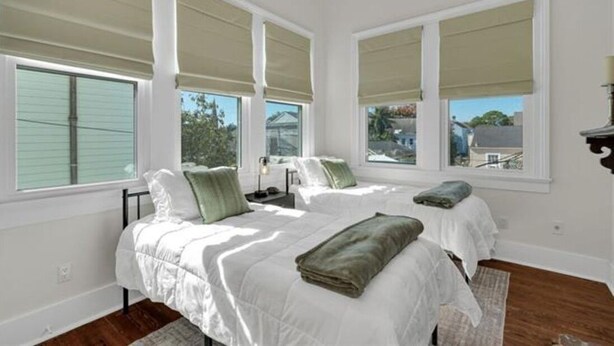 A bedroom with two beds, large windows with beige blinds, a nightstand, and a view of the outside. - Walk everywhere. Stay in comfort. Experience New Orleans like a local, (New Orleans)