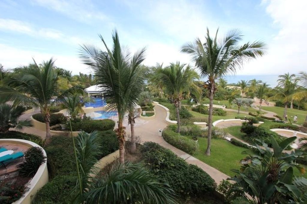 A resort with a pool, palm trees, and a pathway leading to a building.
