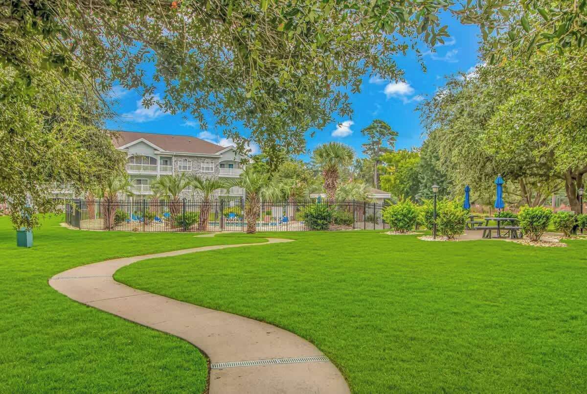 A well-maintained grassy area with a curved pathway leading to a building with a red roof.