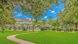A well-maintained grassy area with a curved pathway leading to a building with a red roof. - Bright 1BR Escape, Near Beach, Golf (Myrtle Beach)
