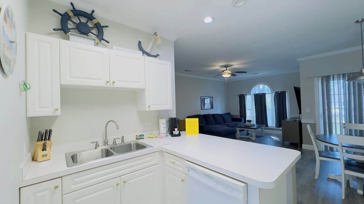 A modern kitchen with white cabinets, a central island, and a dining area with a table and chairs.