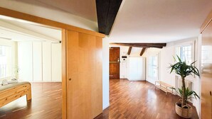 A spacious room with wooden flooring, a bed, a sliding door, and a potted plant. - Loft Piazza Maggiore, comfort in the city center (Bologna)