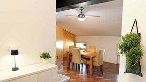 A modern dining area with a wooden table and chairs, a ceiling fan, and a potted plant. - Loft Piazza Maggiore, comfort in the city center (Bologna)