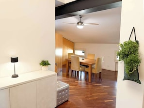 Ein moderner Essbereich mit einem Holztisch, Stühlen, einem Deckenventilator und einem Blumentopf.