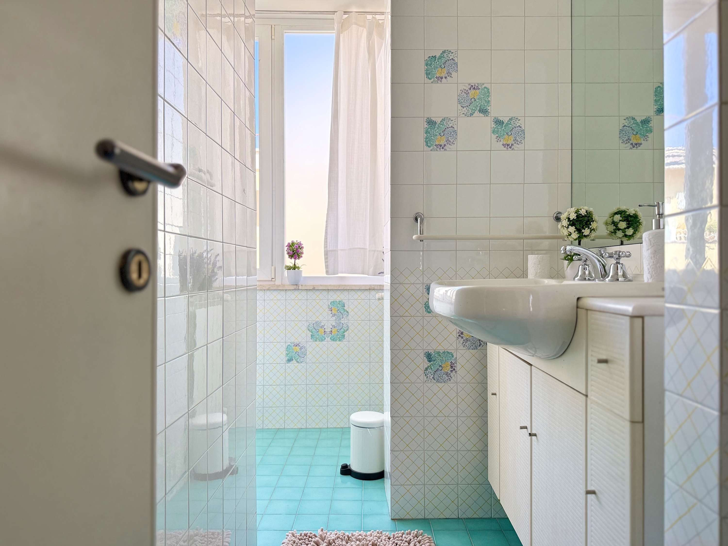 A bathroom with a sink, toilet, and window with curtains.