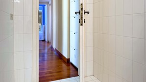 A hallway with white tiled walls and wooden flooring, leading to a room with a door. - Belsito Terrace, Rome Skyline (Roma)